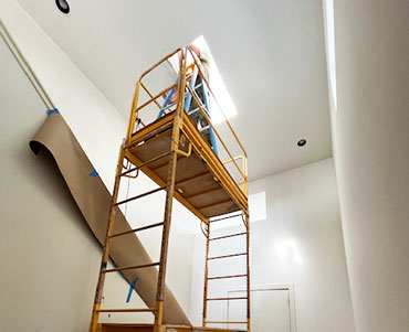 San Marcos Drywall Repair on scaffolding repairing water damaged drywall from skylight leak