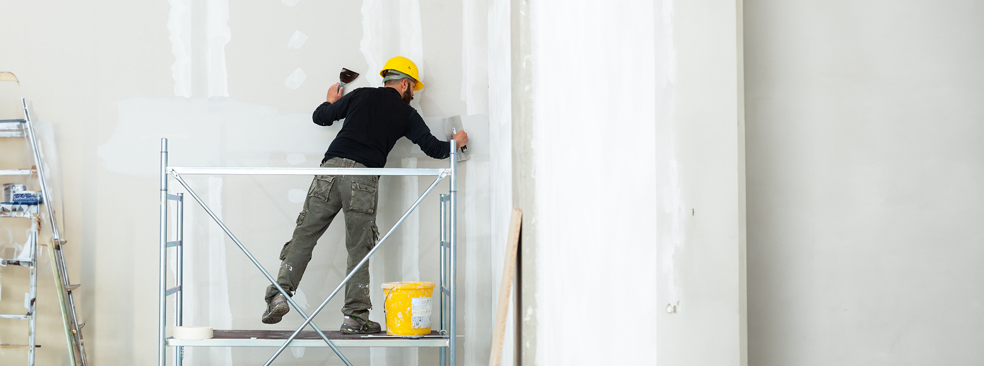 San Marcos Drywall Repair applying joint compound while working from scaffolding